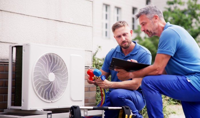 HVAC technicians reviewing an outdoor air conditioning unit in Farmington, UT
