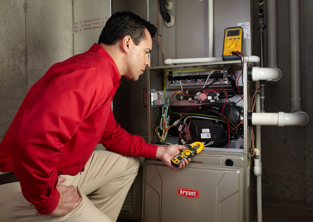 Heating and air conditioning technician servicing an indoor furnace in Farmington, UT