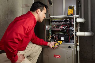 Heating and air conditioning technician servicing an indoor furnace in Farmington, UT